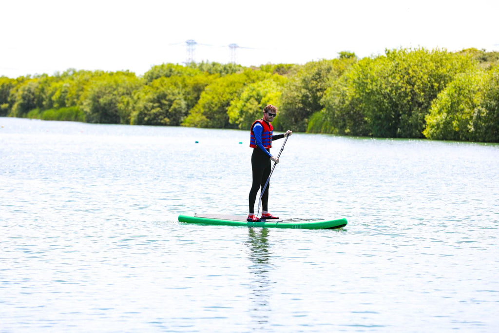 Paddler wearing a life vest on a calm lake surrounded by trees