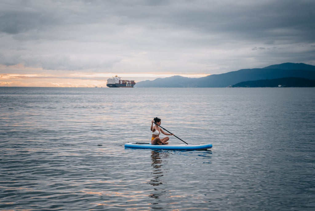 Paddle boarder on calm Pacific Northwest water at sunset